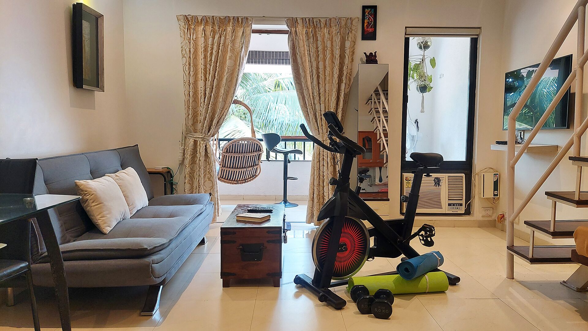 A living room with a sofa, a standing fan, exercise equipment, and a TV.