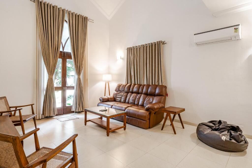 A living room with a leather sofa, wooden coffee table, and rattan chairs.