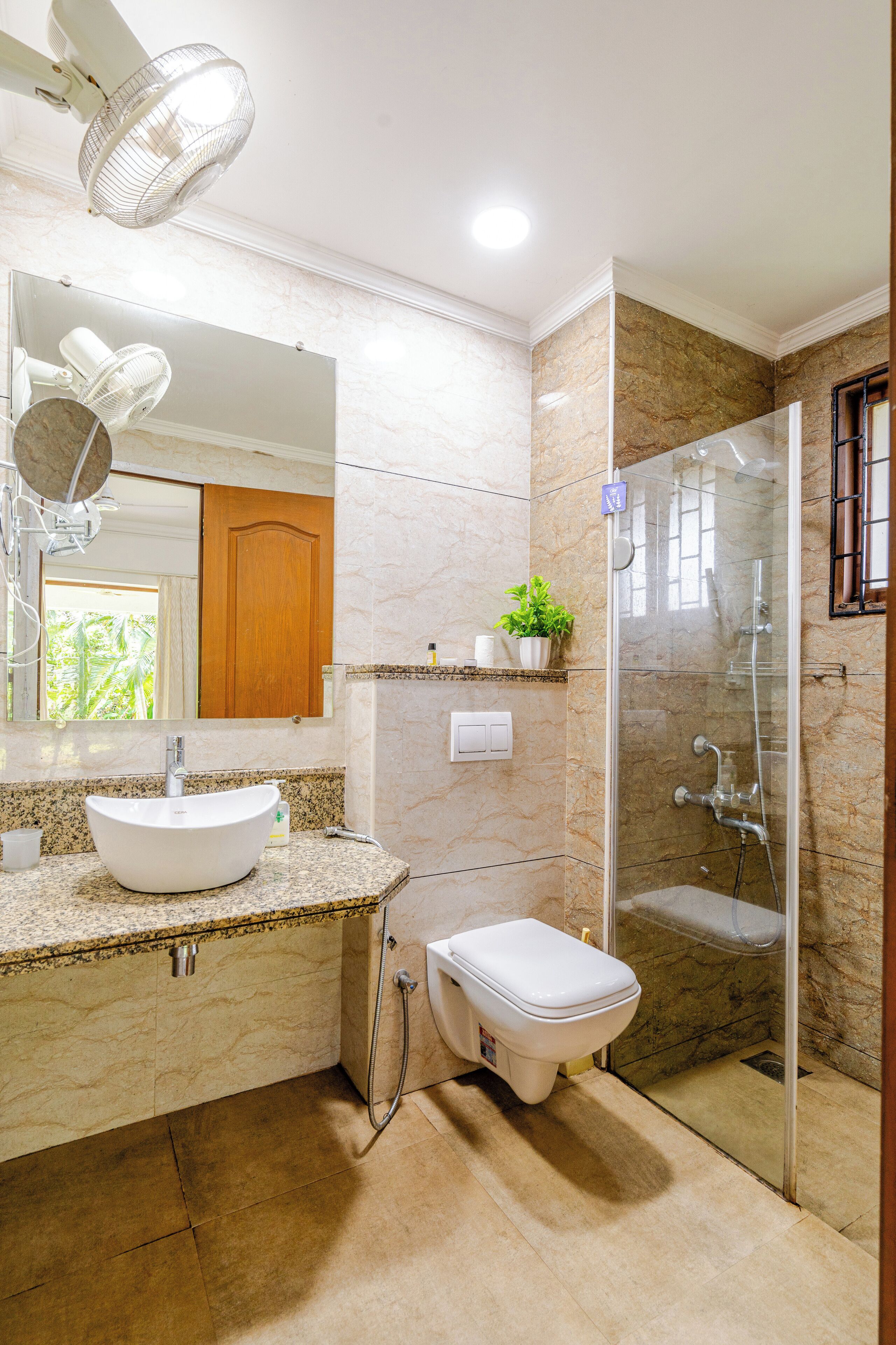 Une salle de bain avec un lavabo en marbre, des toilettes, une douche à parois de verre et un miroir au-dessus du lavabo.