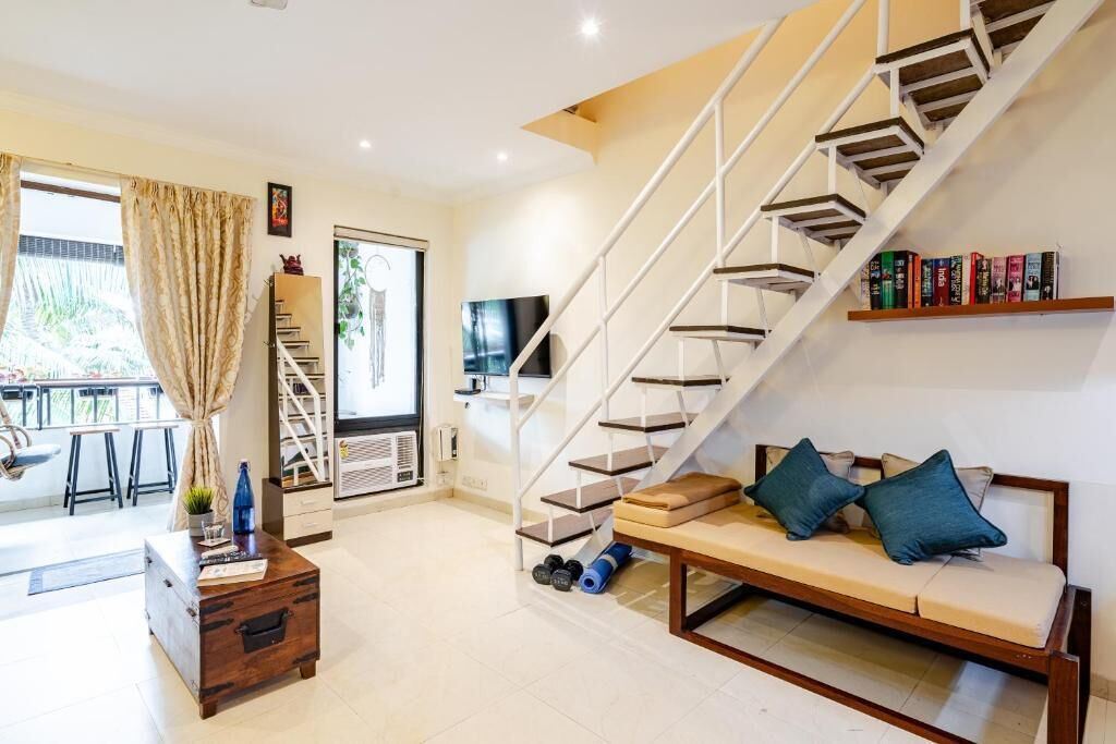 A modern living room with a staircase, a sofa, a coffee table, and a bookshelf.