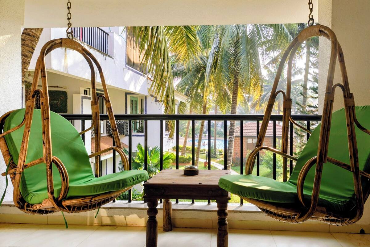 A balcony with two wicker swing chairs and a small table.