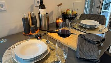 Une table à manger dressée avec des assiettes, des couverts, une bouteille de vin, des verres et une bougie.