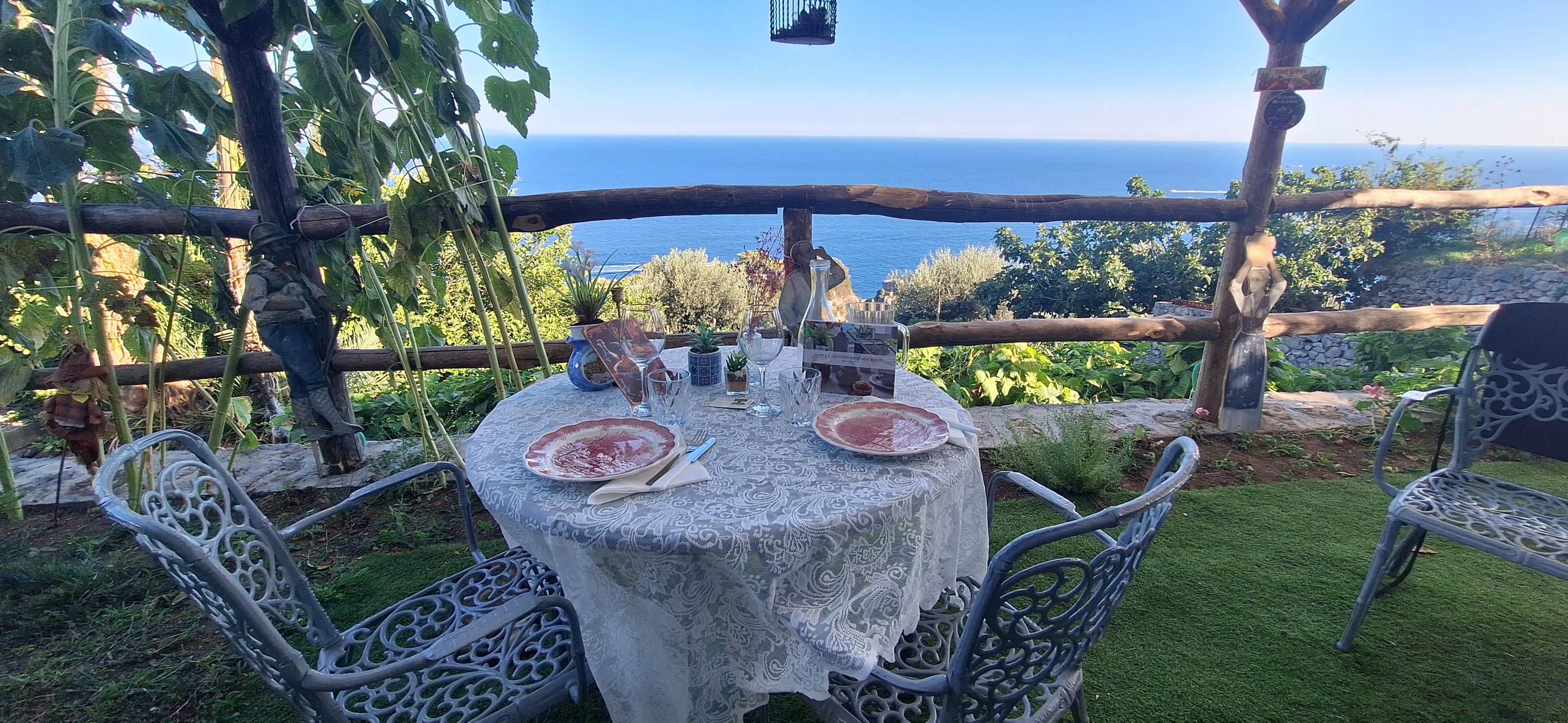 An outdoor dining area with a table set for two, overlooking a scenic view of the sea.