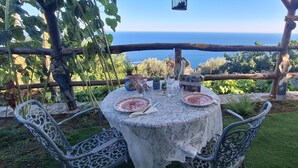 An outdoor dining area with a table set for two, overlooking a scenic view of the sea.