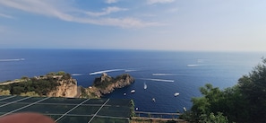 A coastal view with a clear sky, a rocky coastline, and several boats on the water.