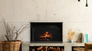 Ein Kamin mit Feuer, ein gewebter Korb und eine Vase mit Trockenpflanzen.