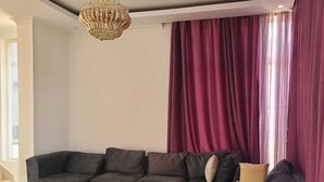 Uma sala de estar moderna com um sofá seccional, uma mesa de centro de madeira e um candelabro.