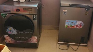 Uma lavanderia compacta com máquina de lavar e frigorífico.