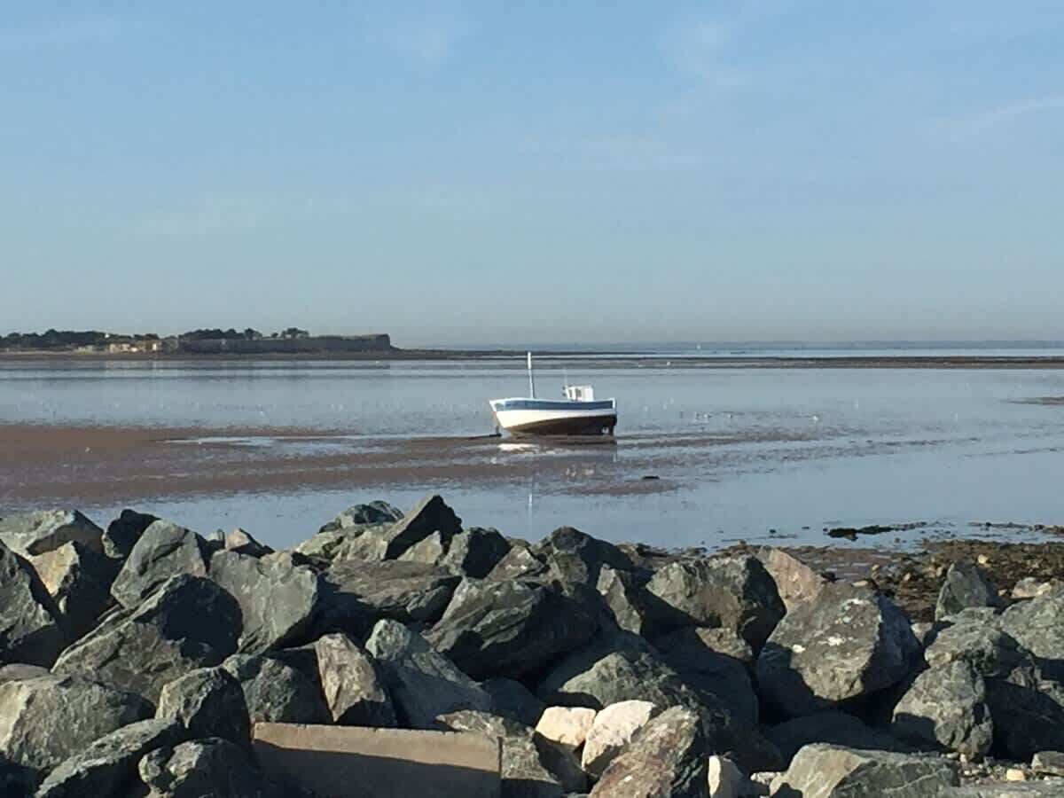Un bateau est amarré près d’une côte rocheuse, sous un ciel dégagé.