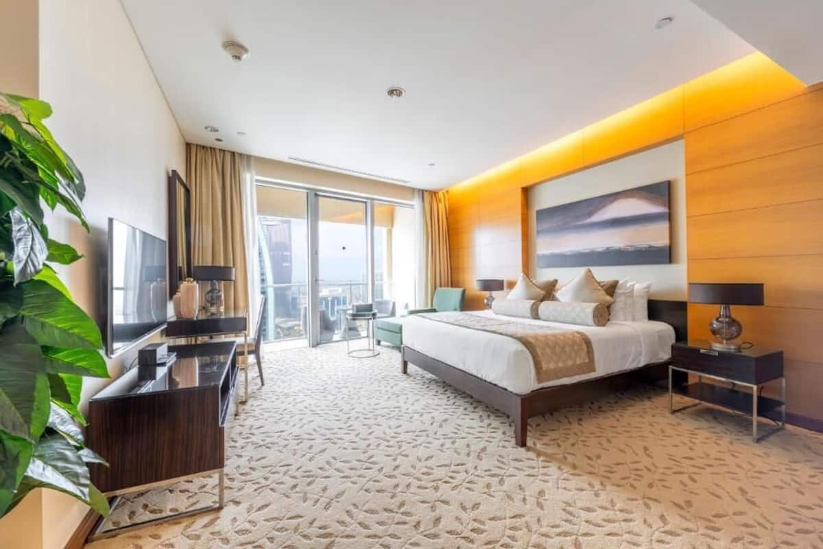 Una habitación de hotel moderna con una cama grande, un televisor de pantalla plana, un escritorio y un balcón con vistas.