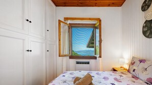 A bedroom with a bed, a window with curtains, a nightstand, and a wall-mounted lamp. - Apartment 'Casa Bell Tramonte' with Lake View, Balcony and Wi-Fi (San Zeno di Montagna)