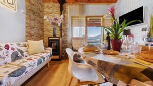 A cozy living room with a sofa, dining table, and chairs, a fireplace, and a view of the outdoors. - Apartment 'Casa Bell Tramonte' with Lake View, Balcony and Wi-Fi (San Zeno di Montagna)