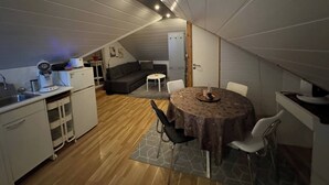 Een kleine keuken met een eethoek, inclusief een tafel en stoelen, in een ruimte met een schuine kap.