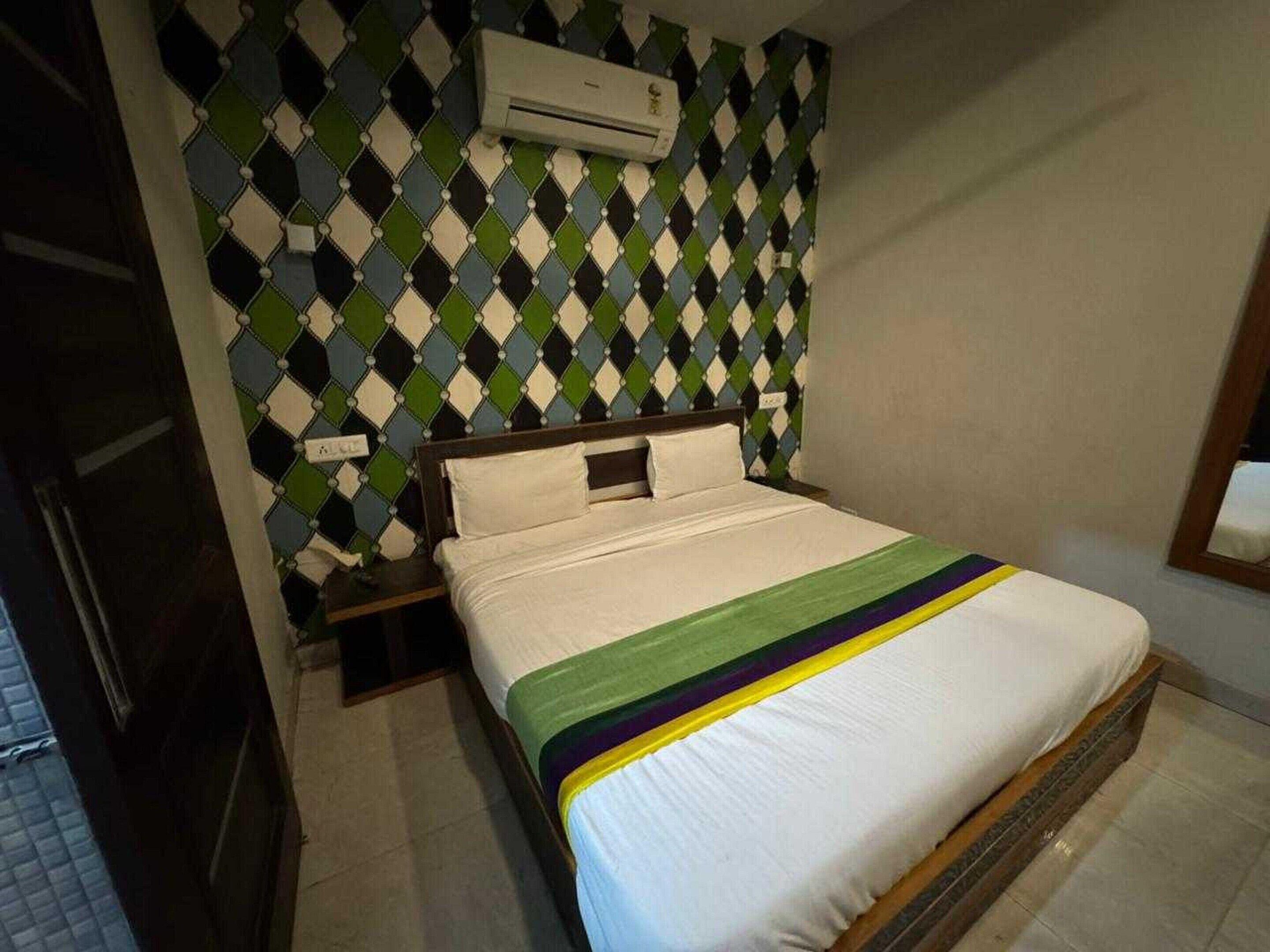 Ein Hotelzimmer mit Bett, Nachttisch, Klimaanlage und einer Wand mit Muster.