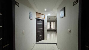 A hallway with doors numbered 104 and 103, leading to a room with a large window and curtains. - Townhouse Ludhiana Railway Junction (Ludhiana)