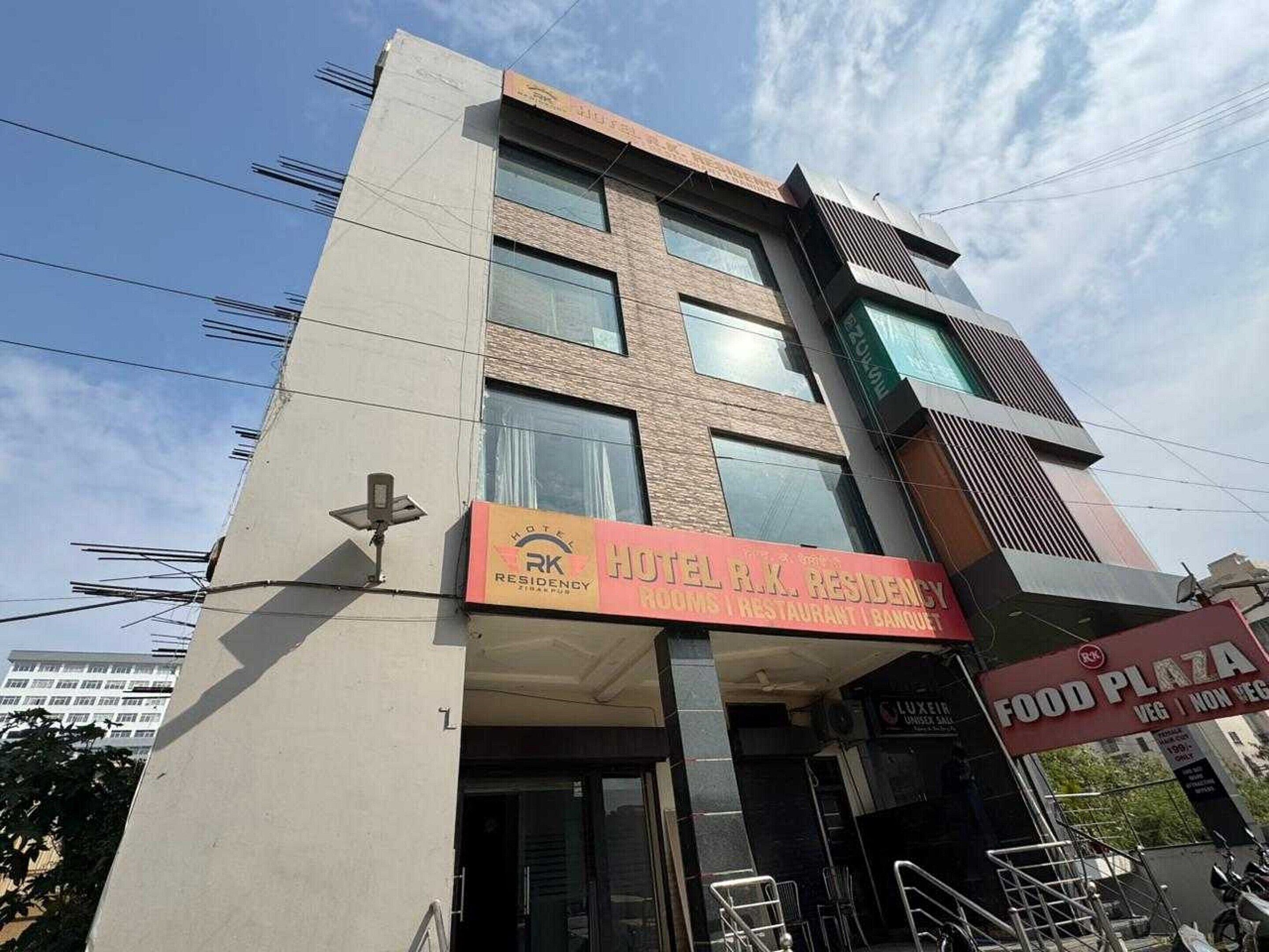 A hotel with a sign for 'Hotel R.K. Residency' offering rooms, restaurant, and banquet services.