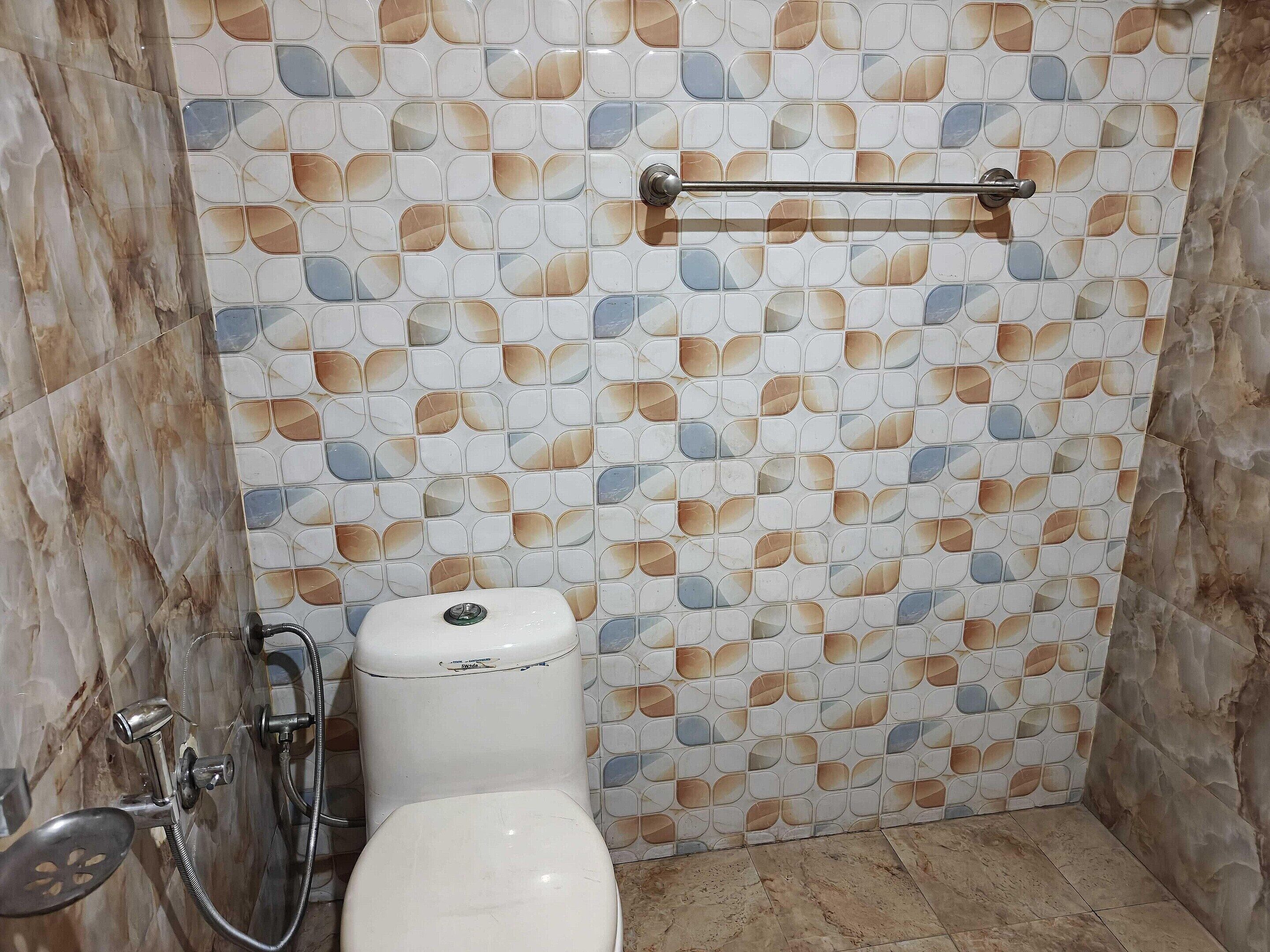 Une salle de bain équipée de toilettes, d’une douche et d’un porte-serviettes.