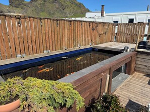 A koi pond with a wooden deck and a mountain backdrop. - The Cozy Caravan Vestmannaeyjar (Vestmannaeyjar)