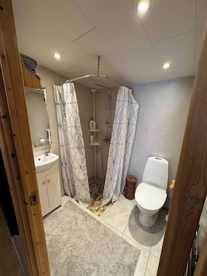 A bathroom with a shower, toilet, and sink. - The Cozy Caravan Vestmannaeyjar (Vestmannaeyjar)