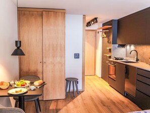 Eine moderne Küche mit Holzausstattung, ein Essbereich mit Tisch für zwei Personen und ein kleiner Hocker.