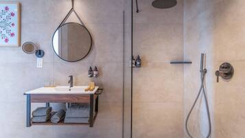 Un baño moderno con ducha envuelta en vidrio, tocador de madera con lavamanos y espejo.
