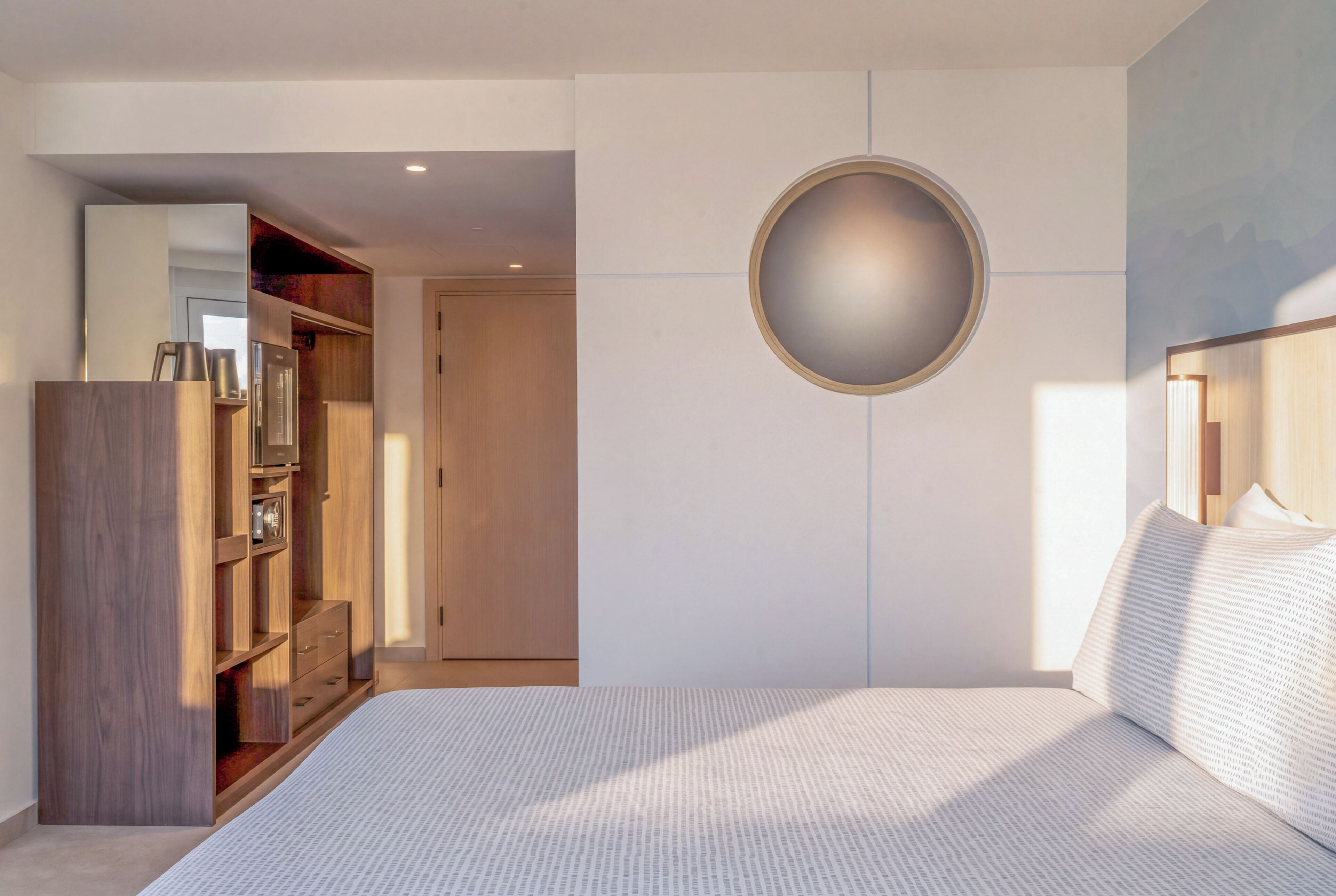 Un dormitorio con una cama grande, un armario, un espejo y un adorno circular en la pared.