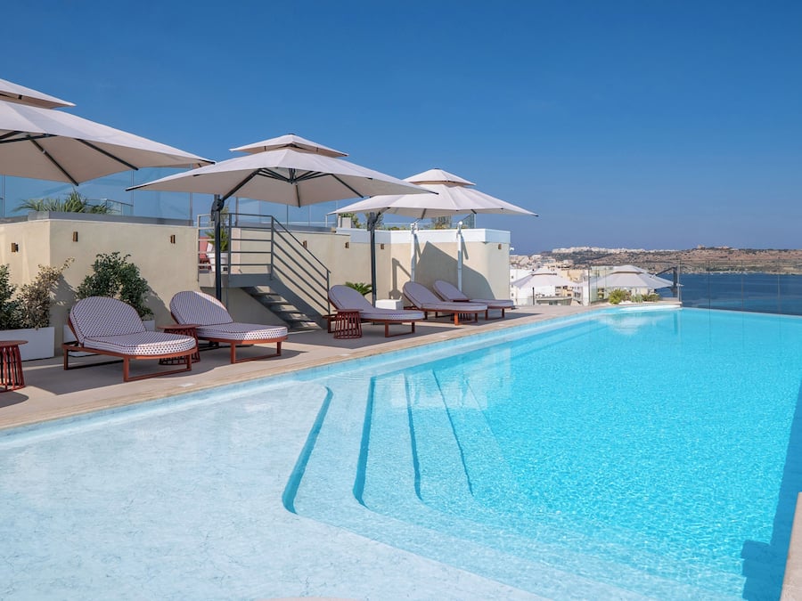 Una piscina techada, una piscina al aire libre, sombrillas