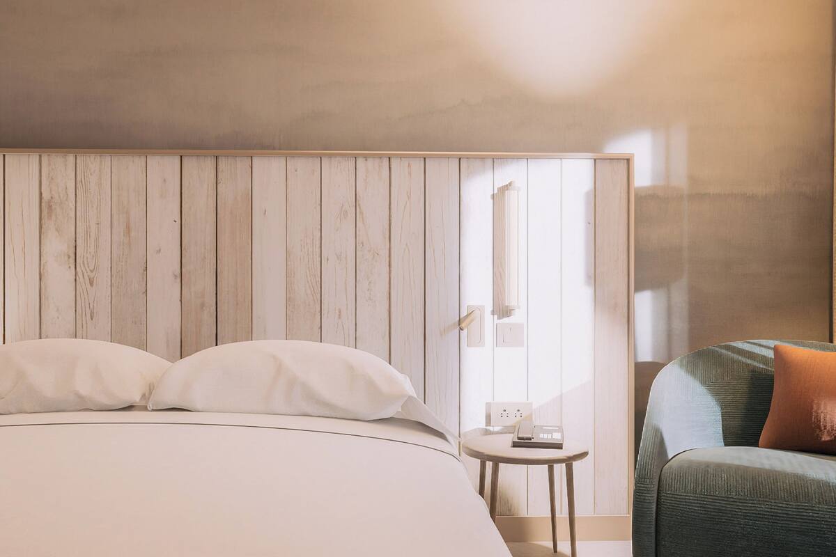 Une chambre à coucher comprenant un lit, une table de chevet, une chaise et un mur recouvert de panneaux en bois.