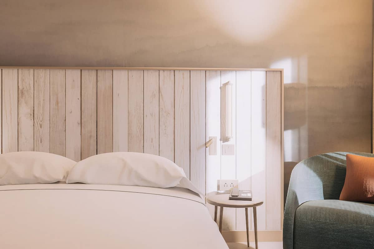 A bedroom with a bed, a nightstand, a chair, and a wooden panel wall.