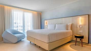 Habitación de hotel moderna con una cama grande, zona de estar y vistas a la ciudad.