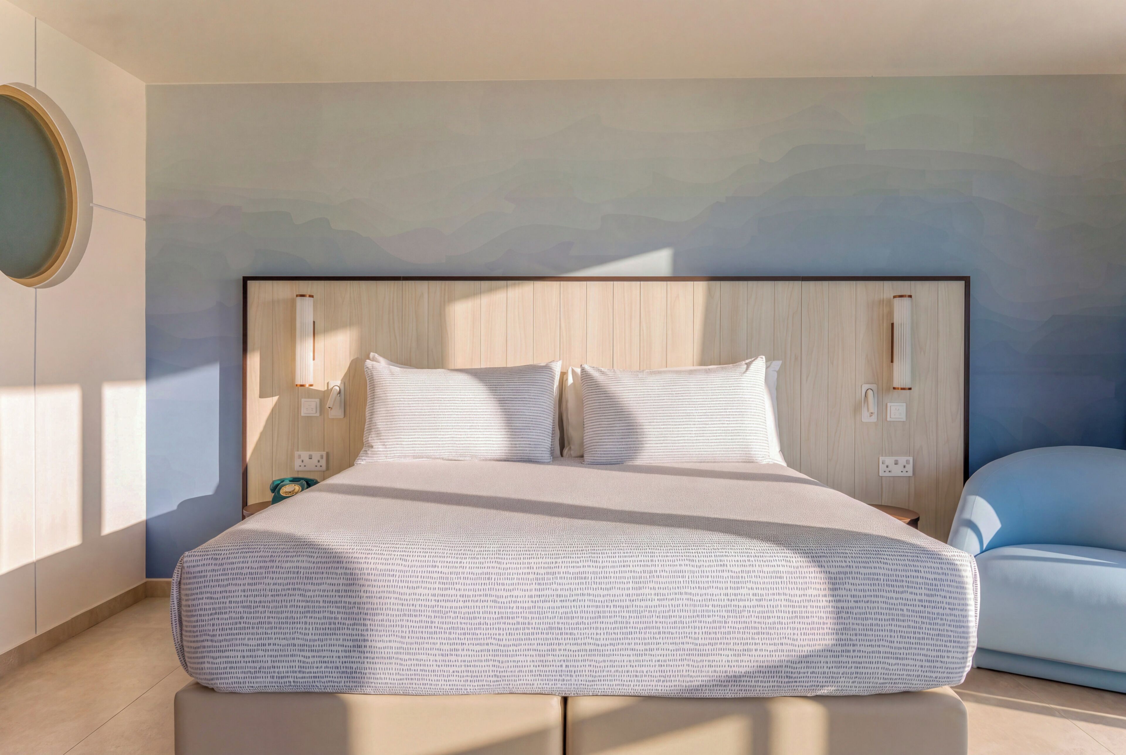 Une chambre moderne avec un grand lit, une tête de lit dotée d’un éclairage intégré et une vue sur le ciel grâce à une ouverture dans le plafond.