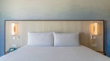 A hotel room with a large bed, two bedside lamps, and a wall-mounted telephone.