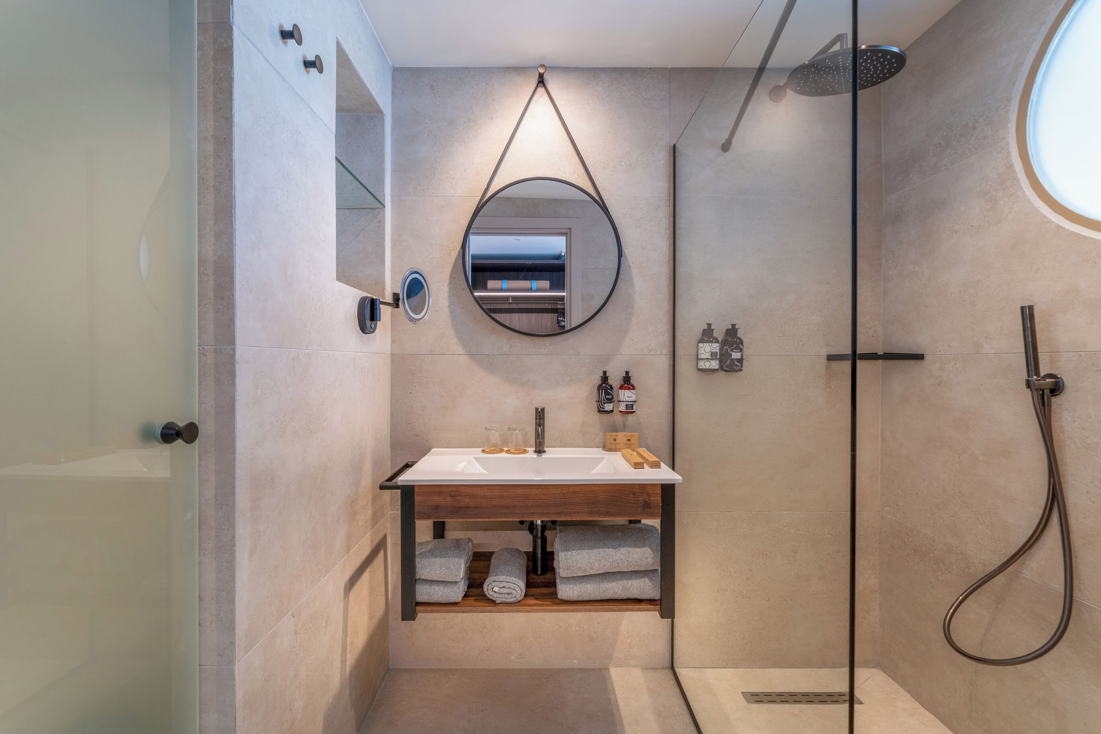 A modern bathroom with a glass shower enclosure, a built-in sink with a mirror, and a towel rack.