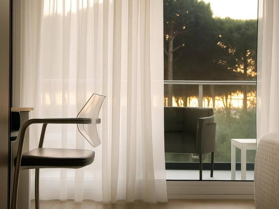 A room with a view of a lake at sunset, a chair, a table, and a sofa.