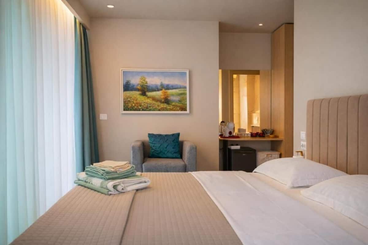 Una habitación de hotel con una cama, una silla, un escritorio y un cuadro en la pared.