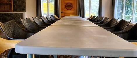 A long dining table with chairs, a patterned floor, and a wooden ceiling with a hanging light fixture.