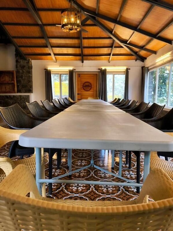 A long dining table with chairs, a patterned floor, and a wooden ceiling with a hanging light fixture. - Gambhiraa Resorts (Kolli Hills)