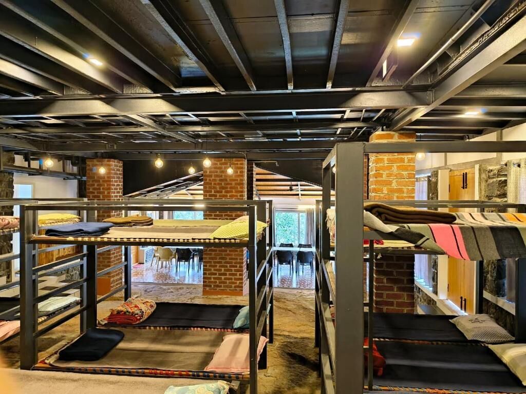 A bunk bed room with metal railings, brick pillars, and a carpeted floor.