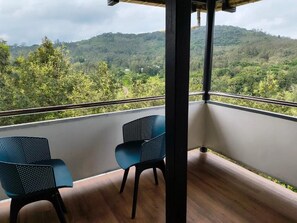 Un balcon avec deux chaises et une vue sur une colline boisée.