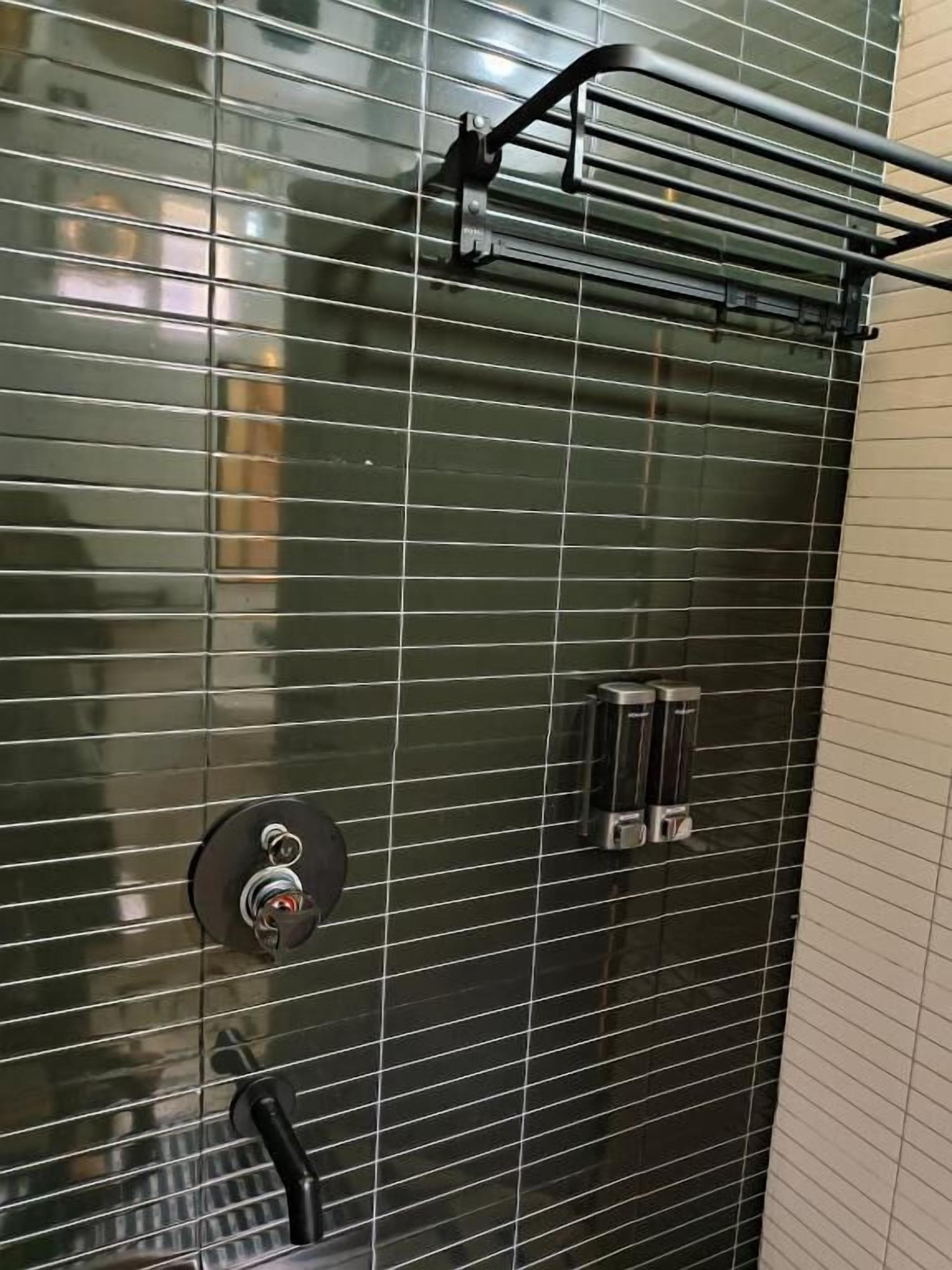 Un bagno con parete piastrellata, porta asciugamani e pannello comandi doccia.