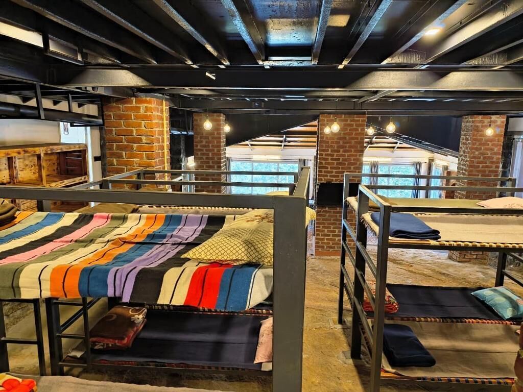 A hostel with bunk beds, brick walls, and a staircase leading to an upper level.