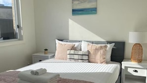 Ein ordentlich eingerichtetes Schlafzimmer mit einem Bett, Nachttischen, einer Lampe und einem Bild an der Wand.