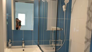 A bathroom with a white sink, a mirror, and a shower.
