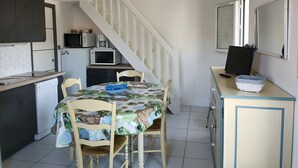 A compact kitchen with a dining table, chairs, and a staircase.