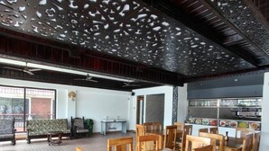 A spacious dining area with wooden tables and chairs, a patterned floor, and a decorative ceiling. - Dandeli River Resort (Dandeli)