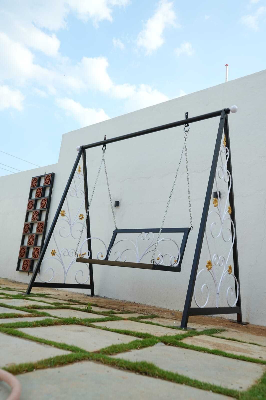 A metal swing set with decorative elements against a white wall.