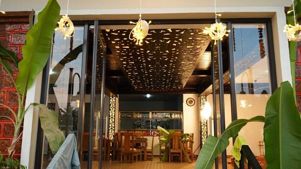 A restaurant with a modern interior, featuring a brick wall, large green plants, and hanging lights. - Dandeli River Resort (Dandeli)