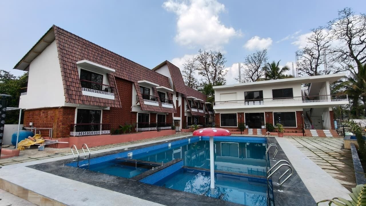 Ein Wohngebäude mit Schwimmbad, rotem Sonnenschirm und Balkon.