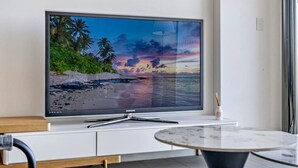 Una TV a schermo piatto su un mobile bianco, con una spiaggia raffigurata sullo schermo.