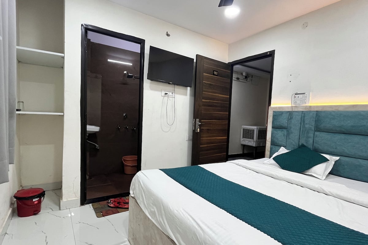 A hotel room with a bed, a shower, a wardrobe, and a TV.